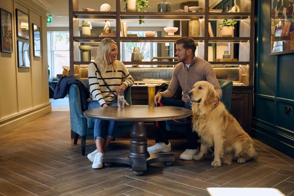 The lounge area within The Leddie Hotel with man, woman and dog enjoying drinks