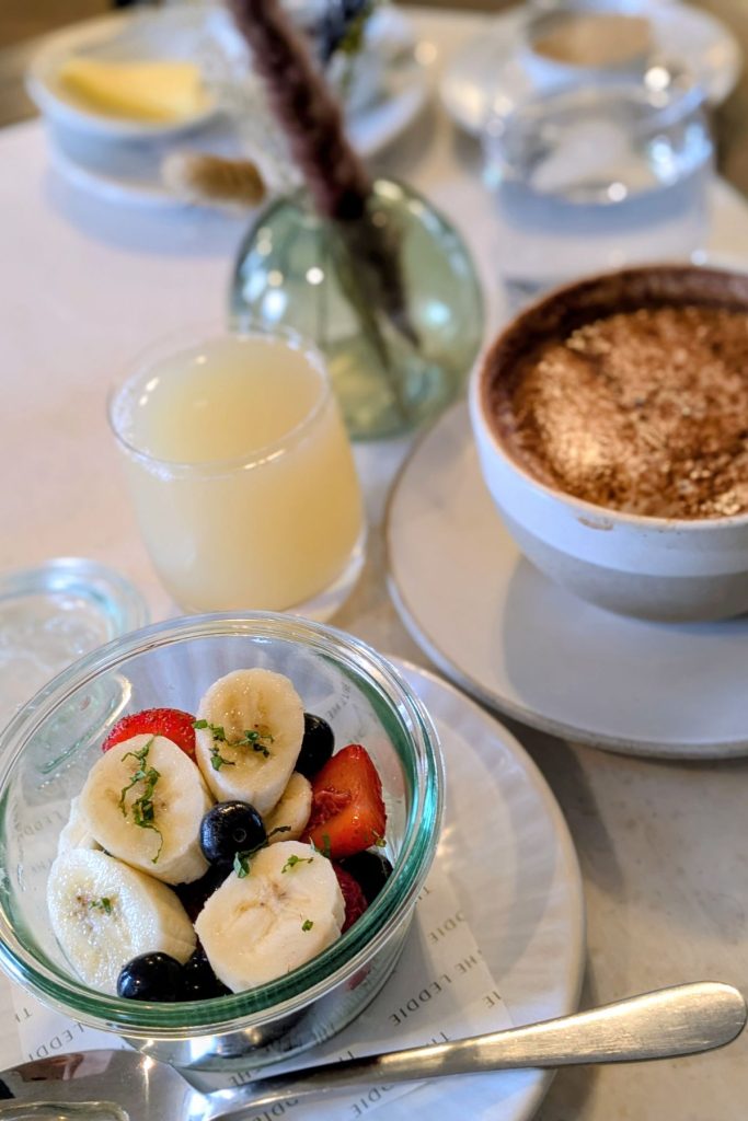 Fruit bowl, apple juice, and hot drink at breakfast